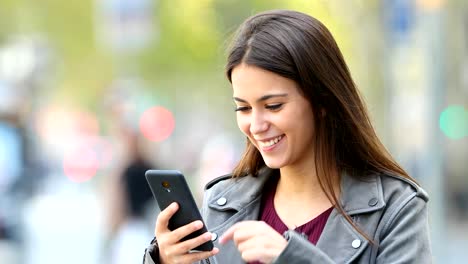 Happy-teen-browsing-on-phone-in-the-street