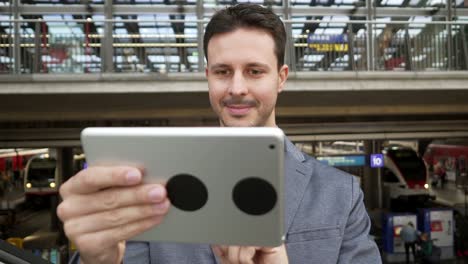 Handsome-young-businessman-writing-texts-on-digital-tablet-in-public-space