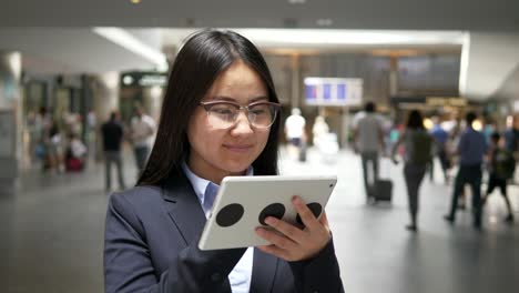 Asiatische-Geschäftsfrau-arbeiten-an-digital-Tablette-am-Flughafen