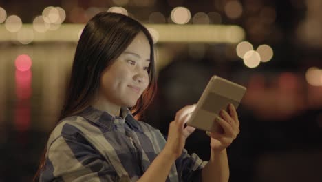 Young-Asian-woman-using-tablet-in-the-city-streets