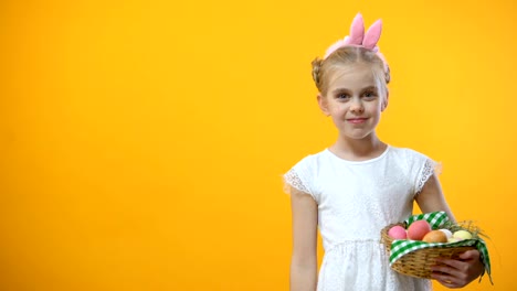 Adorable-schoolgirl-taking-pink-egg-from-basket,-holiday-background,-festival