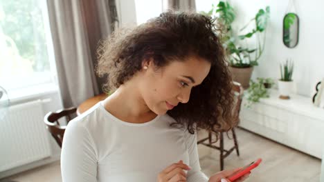 Charming-young-woman-using-phone-at-modern-stylish-apartment.