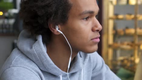 Man-with-earphone-and-mobile-phone-listening-music-at-cafe