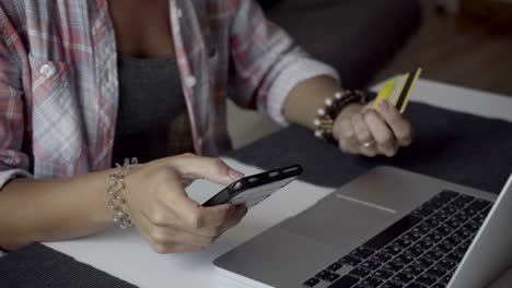 Cropped-shot-of-young-woman-typing-card-number-on-smartphone.