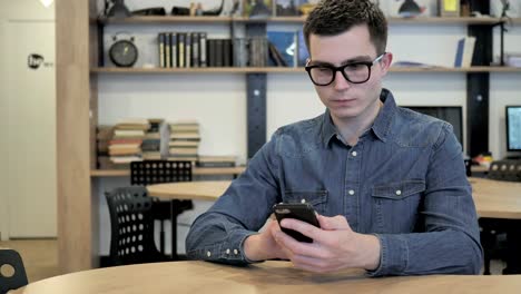 Joven-creativo-en-vidrios-de-navegar-por-Internet-y-el-uso-de-Smartphone