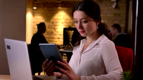 Closeup-portrait-of-young-caucasian-female-office-worker-browsing-on-the-tablet-in-front-of-the-tablet-on-the-workplace