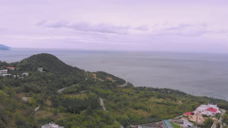 flight-over-hilly-seacoast-with-small-town-under-grey-sky