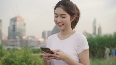 Slow-motion---Cheerful-Asian-tourist-blogger-woman-using-smartphone-for-direction-and-looking-on-location-map-while-traveling-on-the-street-at-city.-Lifestyle-backpack-tourist-travel-holiday-concept.