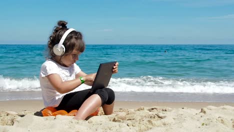 Kid-escribiendo-en-la-tableta-en-la-orilla-del-mar.