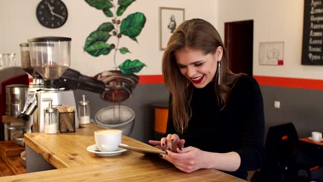 Schöne-junge-Mädchen-in-einem-Café-sitzen-trinken-einen-Kaffee-und-mit-Tablet