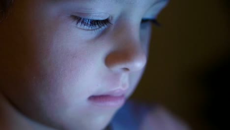 niño-utiliza-la-tableta-o-el-teléfono-por-la-noche-o-por-la-noche-con-la-luz-de-la-noche,-el-concepto-de-e-learning,-aprendizaje-y-tecnologías-simples.-Futurista