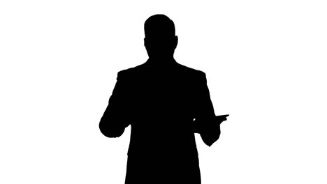 Silhouette-Businessman-swiping-pages-on-a-tablet-and-talking-to-camera-explaining-something-while-walking