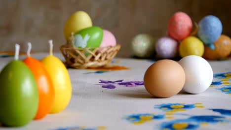 Easter.-male-hand-turns-a-brown-chicken-egg-on-the-table.-olorful-Easter-eggs-in-the-background.