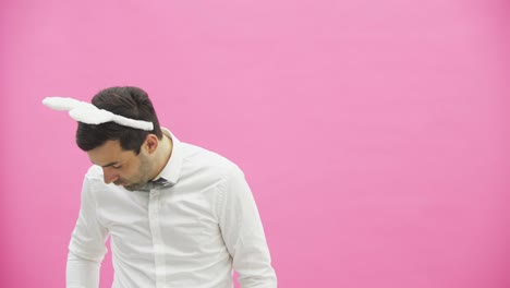 Hermoso-chico-de-pie-sobre-un-fondo-rosa.-Durante-esto-vestido-con-una-camisa-blanca.-Sostener-una-zanahoria-quiere-quemarla-como-un-cigarro.-Después-de-un-tiempo,-tira-zanahorias-al-suelo.