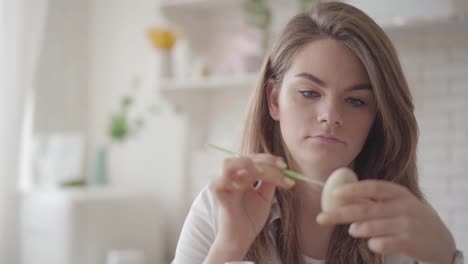 Porträt-der-jungen-Frau,-die-Osterei-mit-einem-kleinen-Pinsel-malt.