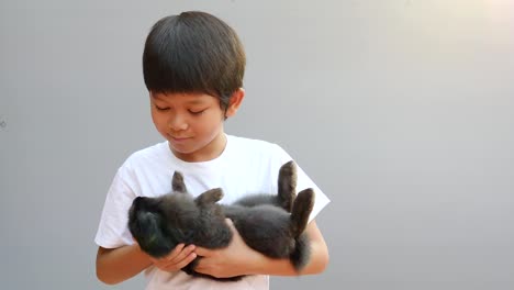 Young-Asian-kid-is-playing-with-lovely-black-rabbit