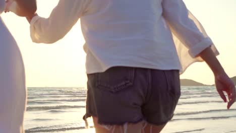 Slow-motion---Young-Asian-lesbian-couple-running-on-beach.-Beautiful-women-friends-happy-relax-having-fun-on-beach-near-sea-when-sunset-in-evening.-Lifestyle-lesbian-couple-travel-on-beach-concept.