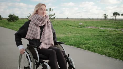 Young-disabled-woman-is-riding-on-wheelchair-in-park-area-in-spring-time