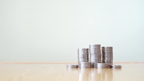 Stop-motion-increasing-pile-of-silver-coins-on-wooden-table-at-right-corner-with-white-color-background