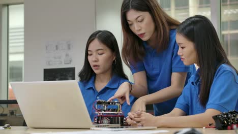 Young-asian-creative-engineers-meeting,-programming-for-collaborative-universal-robotics-at-laptop-in-workshop.-People-with-technology-or-innovation-concept.