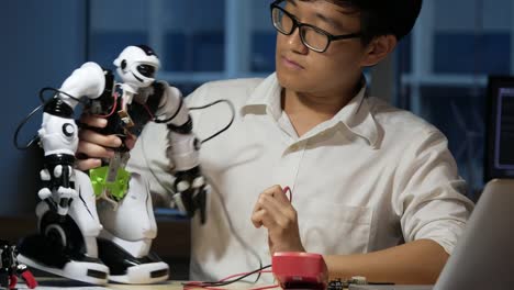 Asiatische-junge-Elektroniker-versuchen,-Roboter-im-Labor-zu-beheben.-Technologie--und-Innovationskonzept.