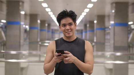 Young-happy-Asian-man-using-phone-at-the-subway-station