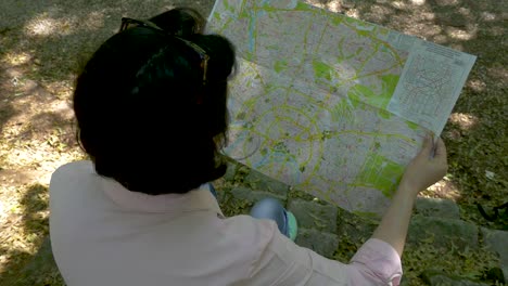 Middle-aged-brunette-looks-at-a-paper-map-in-the-park