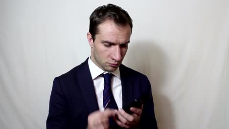 Young-handsome-businessman-pulls-out-his-smartphone-from-his-pocket-and-looks-through-the-news-feed.