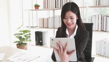 Happy-Attractive-businesswoman-in-black-suit-using-a-digital-tablet-while-sit-in--office-building