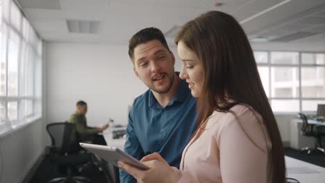 Young-businesswoman-and-businessman-using-digital-tablet-and-discuss-about-new-project-in-modern-office