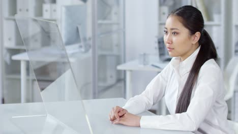 Mujer-Asiática-Joven-usando-pantalla-táctil-TRANSPARENTE-de-AR-en-la-oficina