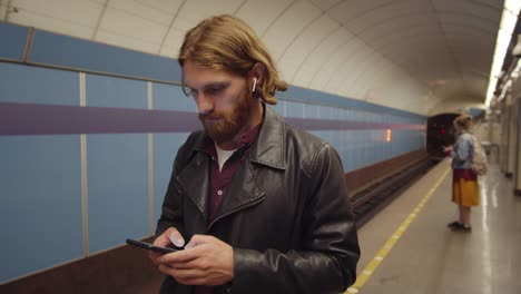 Hombre-pelirrojo-usando-teléfono-en-la-estación-de-metro