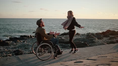 Hombre-discapacitado-y-su-novia-sana-se-están-divirtiendo-en-la-orilla-del-mar,-bailando