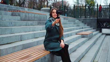 Pretty-vlogger-streaming-from-city-park-using-smartphone-and-steadicam