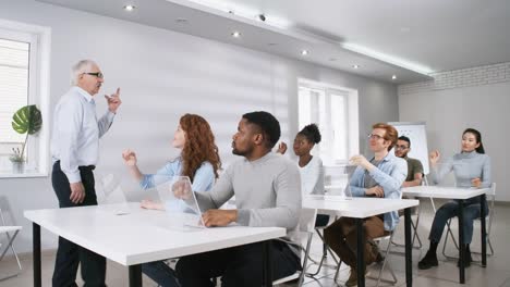 College-Students-Raising-Hands-to-Answer-Questions-at-Futuristic-Lesson