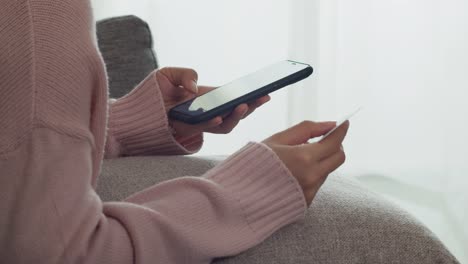 Close-up-hand-of-asian-woman-holding-smartphone-and-credit-card-for-payment-and-shopping-online-at-home.-Happy-woman-making-transaction-using-mobile-bank-application.-Online-shopping-concept.