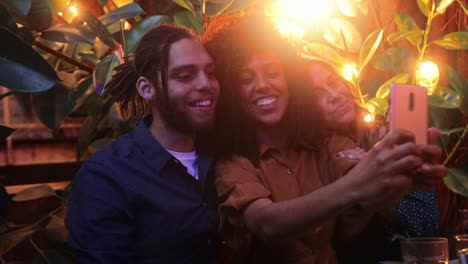 Close-up-black-woman-taking-selfie-with-friends-during-meal