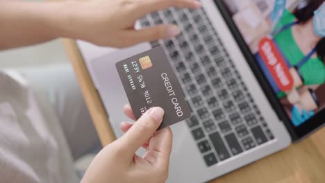 Close-up-consumer-woman's-hand-holding-credit-card-making-e-bank-online-payment-for-purchase-in-online-website-store-with-laptop-computer.-Ecommerce-website-payments.-new-normal-digital-lifestyle