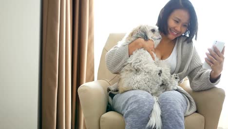 Una-mujer-asiática-Linda-habla-con-su-amiga-usando-su-teléfono-móvil-con-su-perro