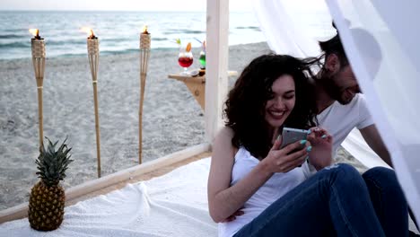 Communicating-through-mobile-phone-on-summer-vacation,-girl-and-guy-browsing-social-network-on-gadget,-summer-season