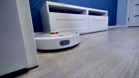 A-robotic-vacuum-moves-along-several-pieces-of-white-furniture.