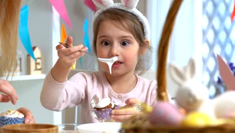 Young-mother-and-her-daughter-wearing-Bunny-ears-cooking-Easter-cupcakes