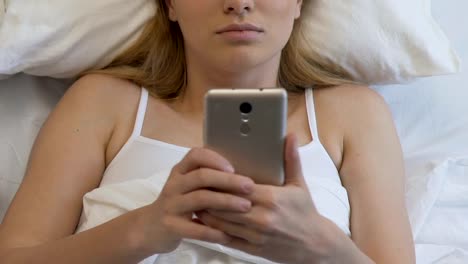 Student-female-with-smartphone-in-bed,-chatting-in-social-networks-until-morning