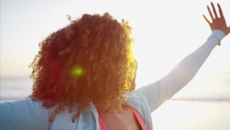 African-American-mujer-relajante-al-amanecer-en-la-playa