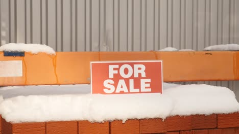 Stapel-von-orange-Lehmziegel-mit-Schnee-"For-Sale"-Wörter