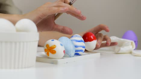 Unrecognizable-woman-puts-an-ornate-Easter-egg-on-a-stand.-Preparing-for-the-holidays.