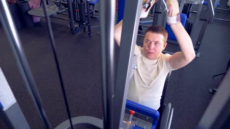 A-disabled-man-is-lifting-weights-in-a-gym-holding-a-metal-handle-by-both-of-his-hands