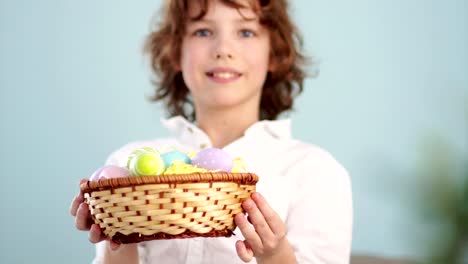 Clouse-ap-Porträt-ein-lockiges-rothaarige-junge-mit-einem-Korb-voller-Ostereier-in-seinen-Händen.-Frohe-Ostern