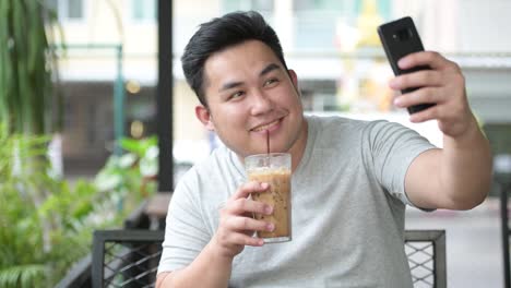 Young-handsome-overweight-Asian-man-relaxing-at-the-coffee-shop