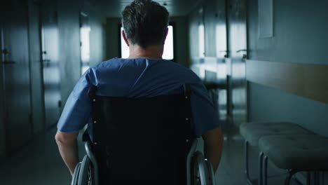 In-the-Hospital,-Front-View-Following-Shot-of-the-Elderly-Man-in-the-Wheelchair-Moving-through-the-Hallway.